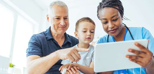 Female doctor showing son and father something on handheld tablet screen